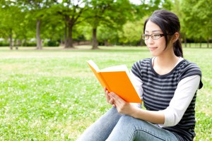 asian woman reading a book in the park